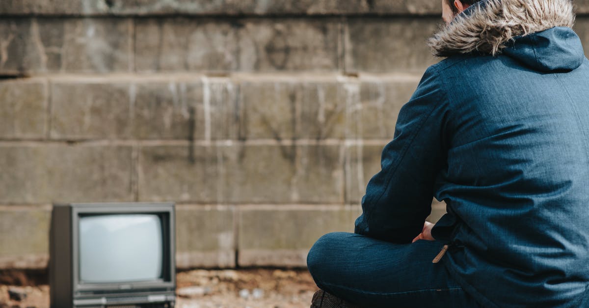Crossing the US-Canadian border and back - Crop man sitting against vintage TV on street Crossing the US-Canadian border and back - Crop man sitting against vintage TV on street