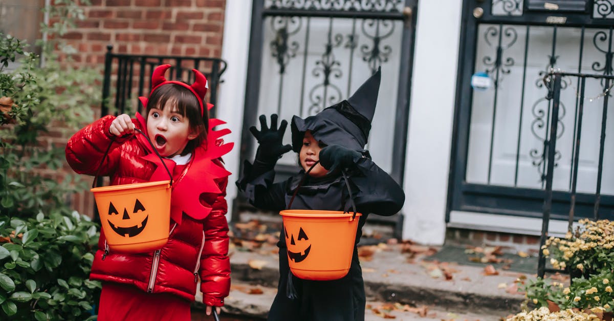 Culture Day in Osaka/Kyoto - Funny children in witch and devil costumes carrying buckets for candies and showing creepy grimaces against house in neighbourhood Culture Day in Osaka/Kyoto - Funny children in witch and devil costumes carrying buckets for candies and showing creepy grimaces against house in neighbourhood