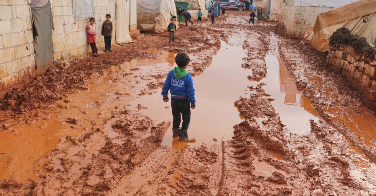 Cumbria Way in June. Do I need to make reservations? - Group of children standing on dirty wet ground with puddles between old tents in refugee camp with in poor settlement Cumbria Way in June. Do I need to make reservations? - Group of children standing on dirty wet ground with puddles between old tents in refugee camp with in poor settlement