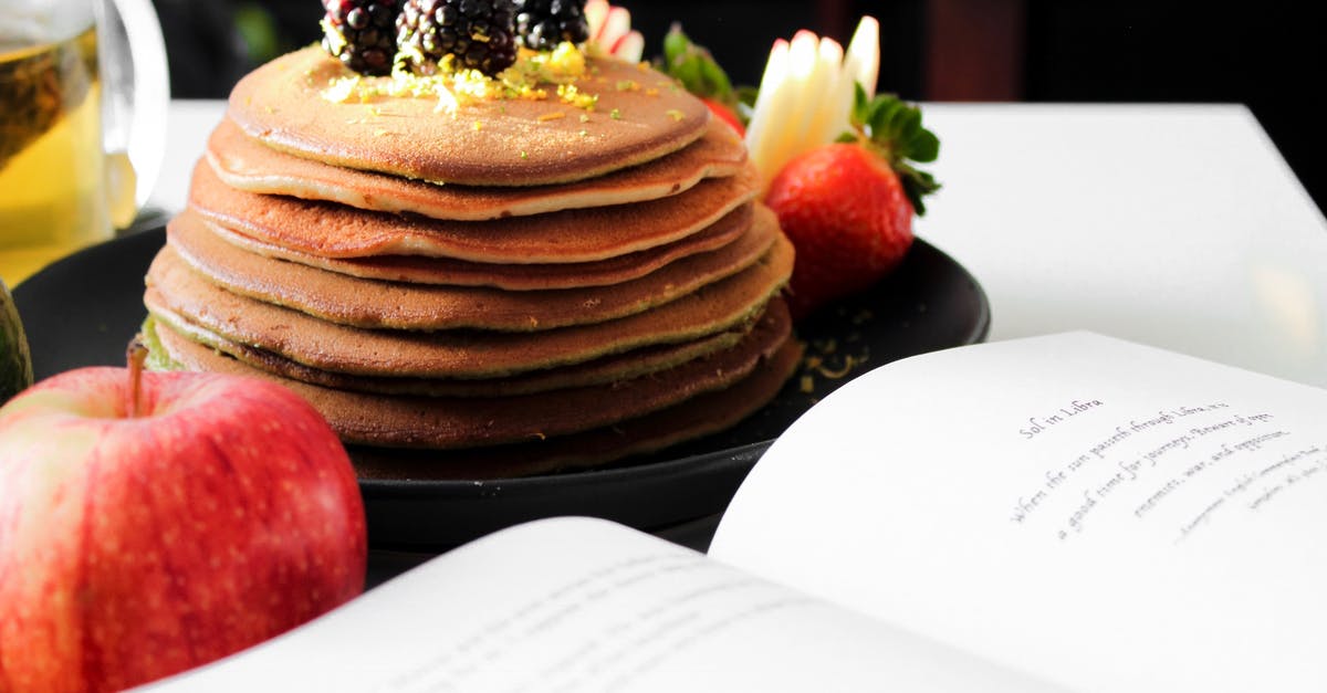 Custom Rules in Canada about bringing food - Delicious appetizing pancakes on black plate with blackberries on top and apple near opened book Custom Rules in Canada about bringing food - Delicious appetizing pancakes on black plate with blackberries on top and apple near opened book