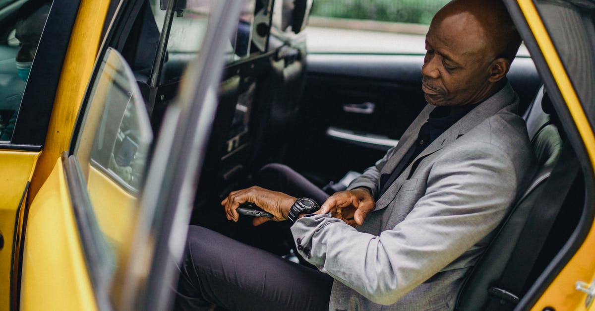 Delays in SFO in late February - Serious black businessman checking time on wristwatch in taxi Delays in SFO in late February - Serious black businessman checking time on wristwatch in taxi