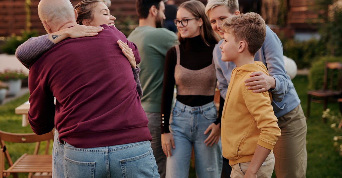 Dependent unemployed adult sons not getting visa to UK. Would it be reasonable to plan a family holiday for all to meet up in Europe or Canada? - Happy friends embracing in summer yard