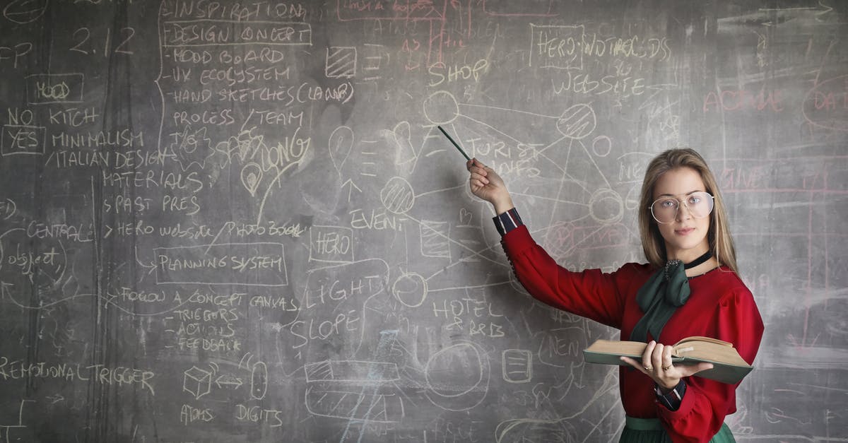 Determine Cathay Pacific fare class - Serious female teacher wearing old fashioned dress and eyeglasses standing with book while pointing at chalkboard with schemes and looking at camera Determine Cathay Pacific fare class - Serious female teacher wearing old fashioned dress and eyeglasses standing with book while pointing at chalkboard with schemes and looking at camera