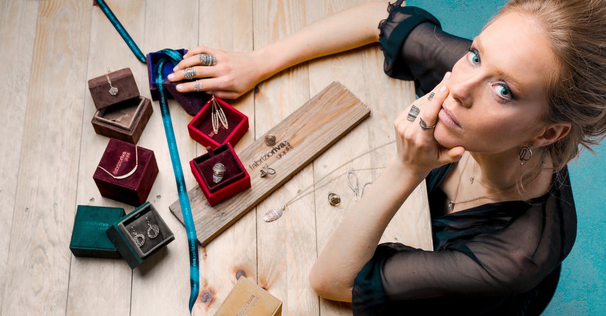 Did not declare jewelry from Aruba - From above serious businesswoman looking up at camera while sitting at wooden table with small jewelry boxes with bijouterie and decorating with ribbon as present Did not declare jewelry from Aruba - From above serious businesswoman looking up at camera while sitting at wooden table with small jewelry boxes with bijouterie and decorating with ribbon as present