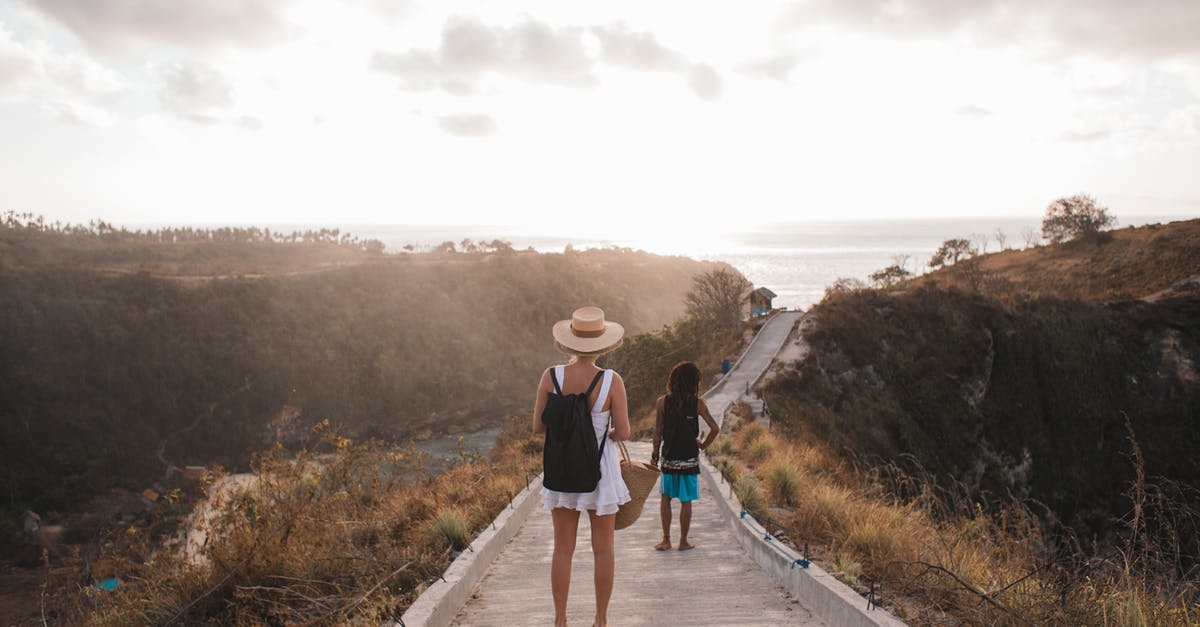 Difference between air fare for same route - Unrecognizable mother with daughter contemplating shiny sky from walkway Difference between air fare for same route - Unrecognizable mother with daughter contemplating shiny sky from walkway