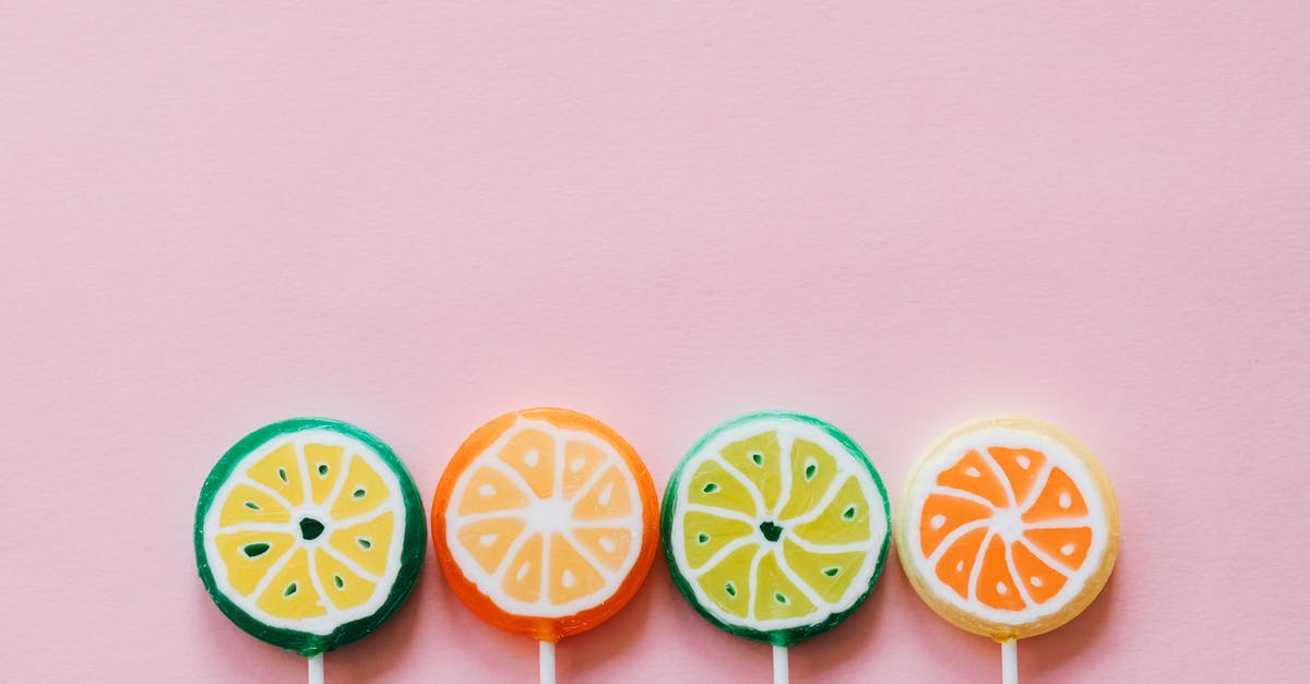 Different passengers for round trip [duplicate] - Top view of round multicolored candies with citrus fruit flavor on thin plastic sticks on pale pink surface