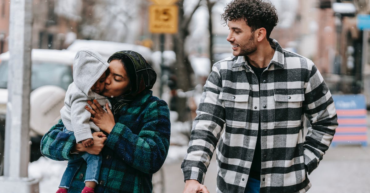 Do airlines count child carriers / baby backpacks as strollers? - Tender multiracial family walking on street with black baby Do airlines count child carriers / baby backpacks as strollers? - Tender multiracial family walking on street with black baby