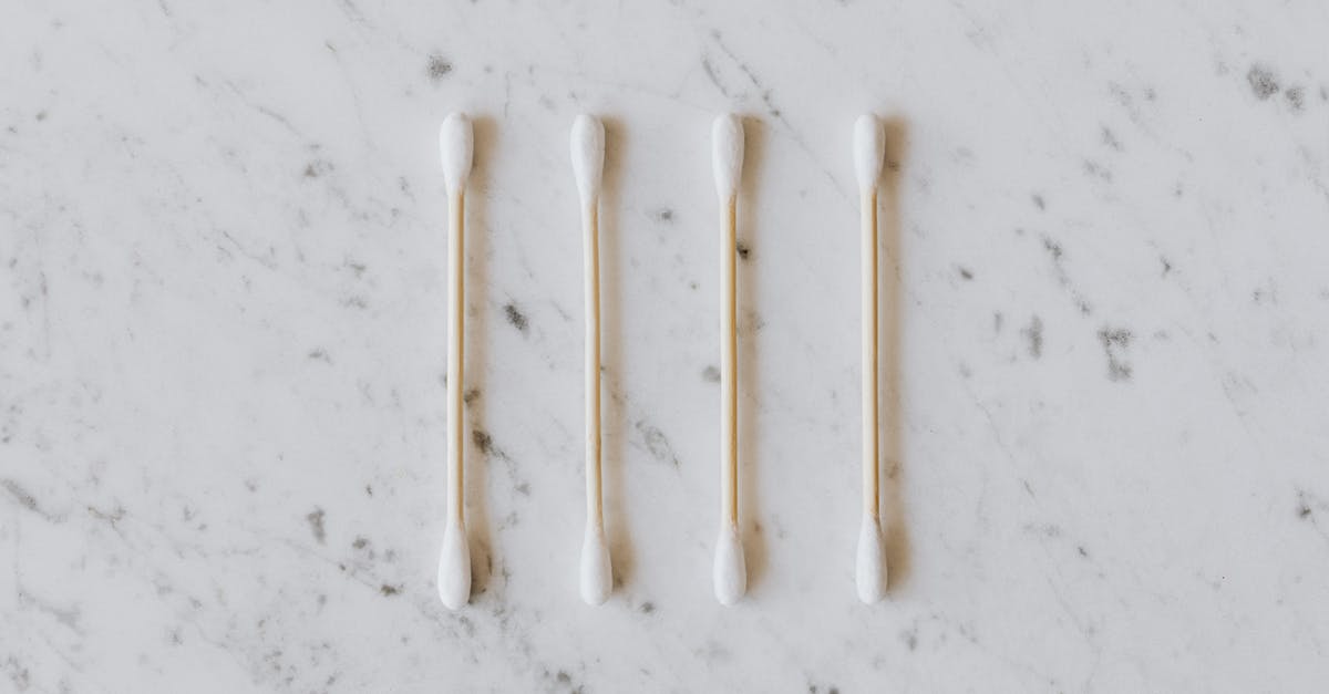Do ear wax cleaning salons provide related, similar services? - Top view of identical cotton swabs on thin wooden sticks with soft rounded edges on marble surface with tiny spots and gray lines Do ear wax cleaning salons provide related, similar services? - Top view of identical cotton swabs on thin wooden sticks with soft rounded edges on marble surface with tiny spots and gray lines