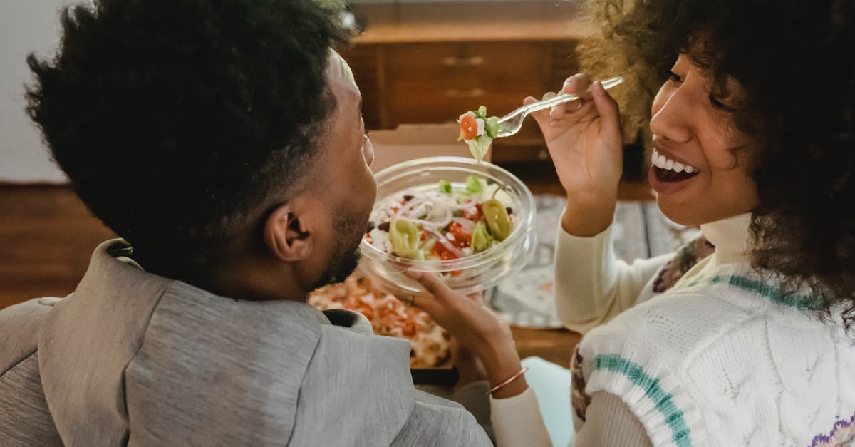 Do home deliveries of food in the USA have "anti-tampering stickers" on them? [closed] - Happy young ethnic woman feeding boyfriend with salad while sitting on couch