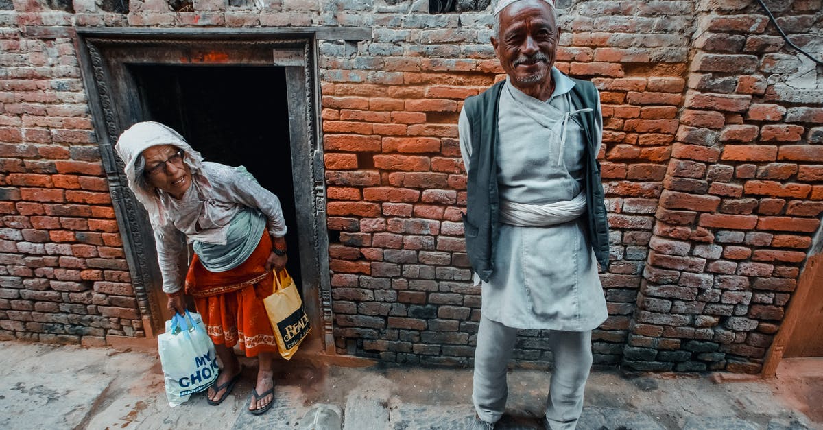 Do I have any options for getting a delayed bag back from behind customs in Montreal? - From above of smiling ethnic man in traditional outfit near attentive female with plastic bags at door of aged brick building in city Do I have any options for getting a delayed bag back from behind customs in Montreal? - From above of smiling ethnic man in traditional outfit near attentive female with plastic bags at door of aged brick building in city