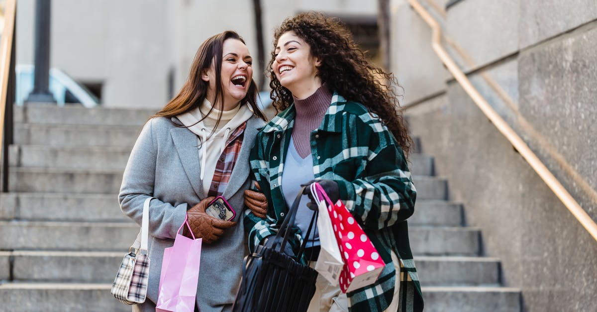 Do I have to go through customs, recheck my bag, during my Heathrow layover? - Joyful young stylish multiracial female best friends in trendy warm clothes laughing while walking downstairs with shopping bands in hands on city street Do I have to go through customs, recheck my bag, during my Heathrow layover? - Joyful young stylish multiracial female best friends in trendy warm clothes laughing while walking downstairs with shopping bands in hands on city street