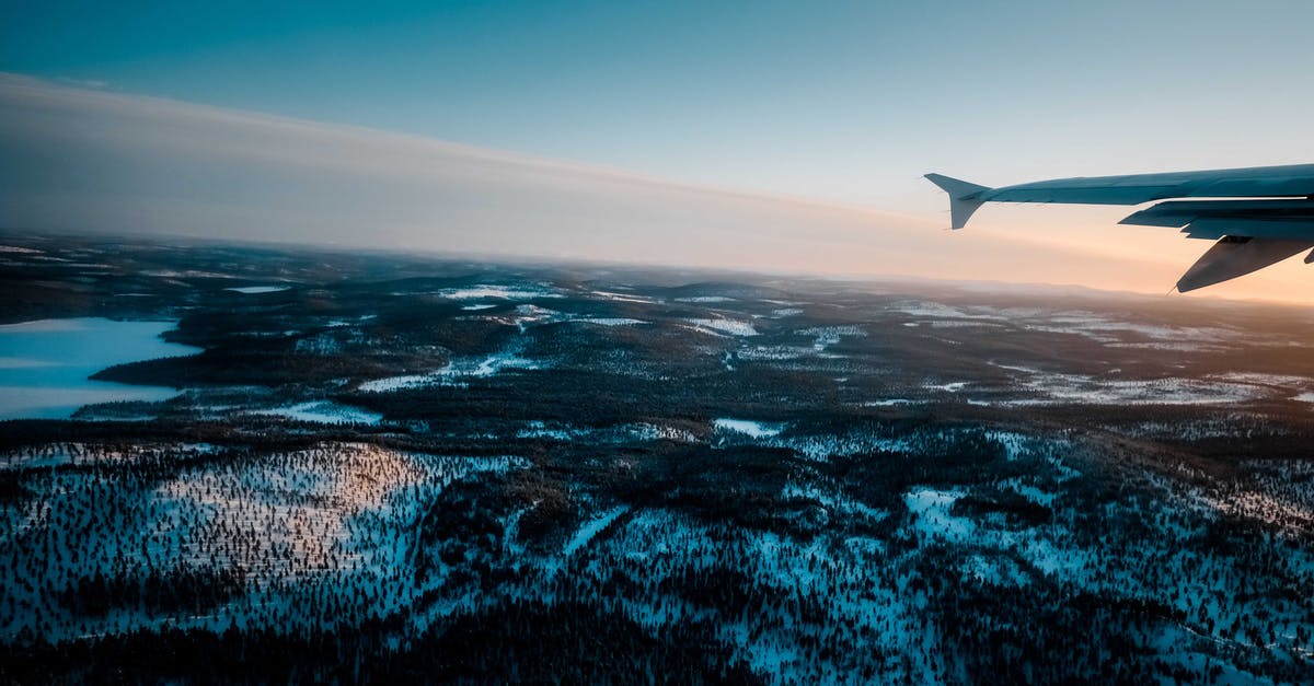 Do I need a passport to fly from UK to Bulgaria through Istanbul? - Plane flying over snowy terrain with trees and lake at sundown