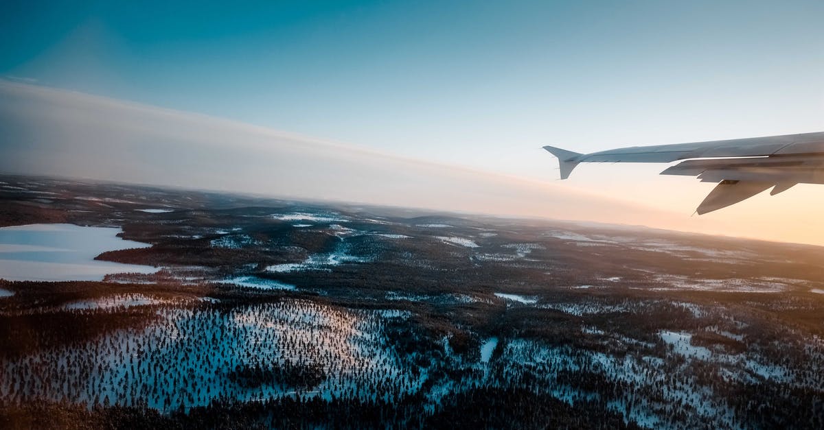 Do I need a passport to fly from UK to Bulgaria through Istanbul? - Through window of wing of modern aircraft flying over snowy terrain with lush trees and frozen lake at sunrise