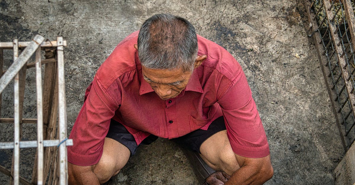 Do I need a passport to return from Canada? - From above of anonymous ethnic male squatting on dirty floor near grid on street in poor district of rural area