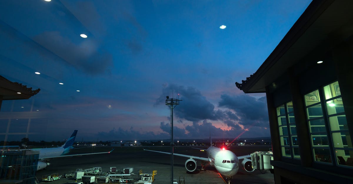 Do I need a transit visa at Haneda when self transferring? - Contemporary airplanes with red beacon parked on airfield near airport service vehicles and terminal at night