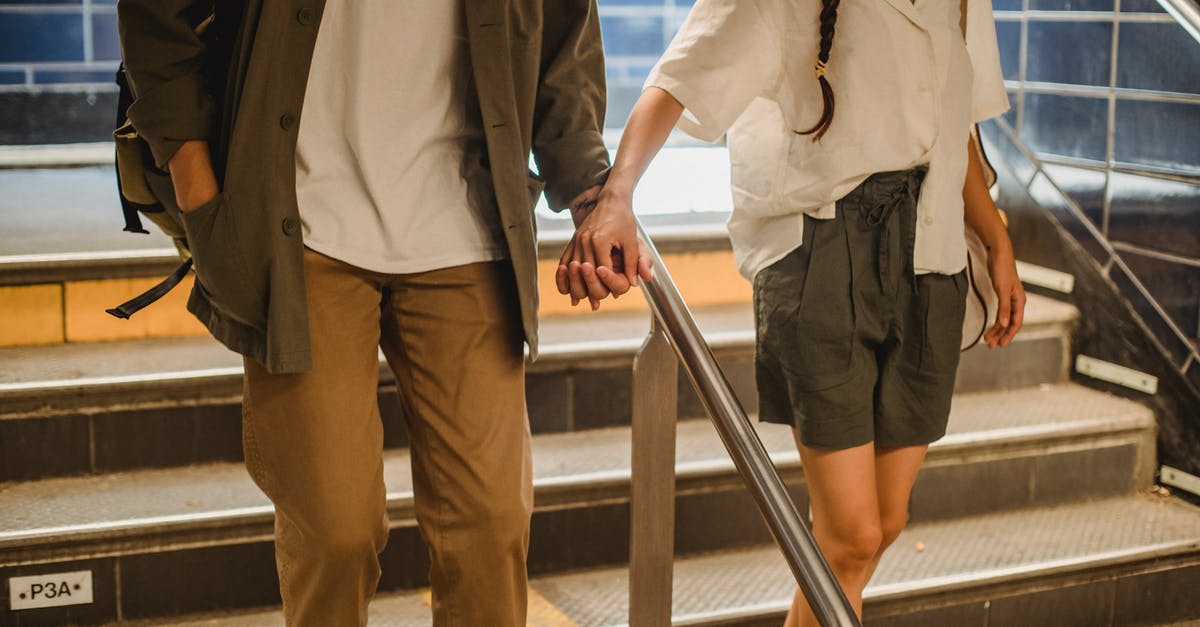Do I need a transit visa or anything to visit the city while on a layover in Amsterdam? if am holding a Schengen visa [duplicate] - Faceless young trendy couple holding hands while going downstairs in metro station