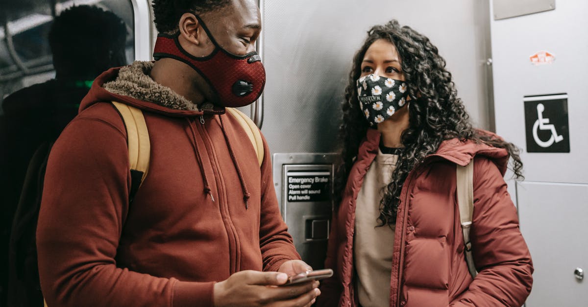 Do I need a Visa for a Schengen train trip with stop-over in other Schengen countries? [duplicate] - Multiethnic couple in masks with smartphone talking on subway