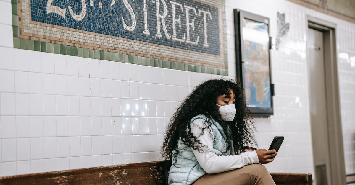 Do I need a visa to Transit US? [duplicate] - Focused African American female in casual clothes browsing mobile phone while sitting on bench in New York underground platform