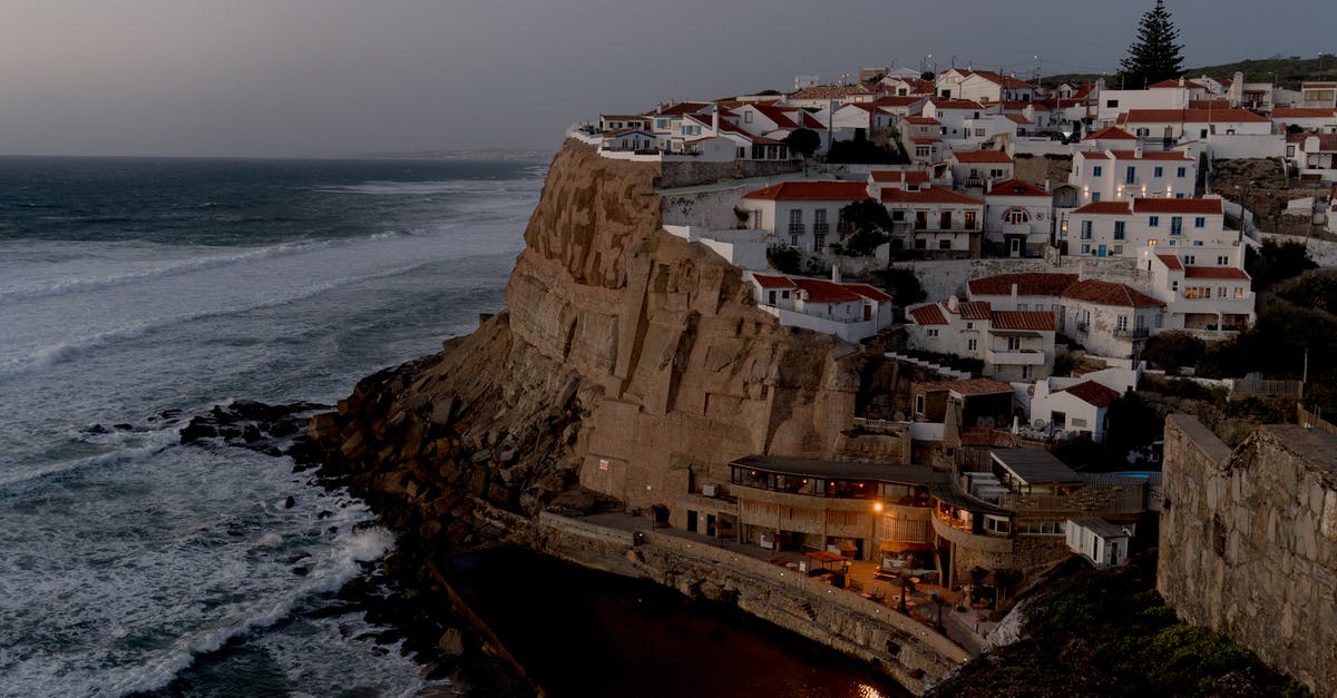 Do I need Schengen travel insurance to visit Portugal if covered by the NHS? - Houses Perched on a Cliff Overlooking a Sandy Beach and Rocky Coastline Do I need Schengen travel insurance to visit Portugal if covered by the NHS? - Houses Perched on a Cliff Overlooking a Sandy Beach and Rocky Coastline