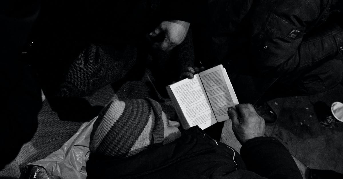 Do I need to book a taxi before arriving at Paris La Défense? - Black and white of homeless man lying on floor and reading book in night shelter for homeless