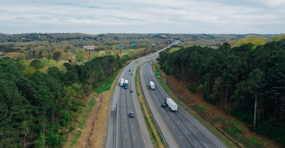 Do I need to pre-register my foreign car to drive in Milan's Zone B? - Aerial view of wavy asphalt roads with driving cars and trucks between bright trees under endless cloudy sky in rural zone