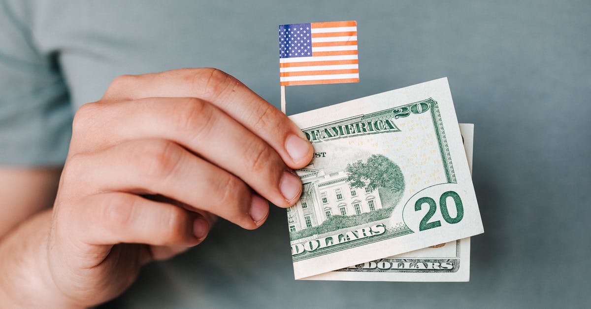 Do I need to take cash on my holiday to Sardinia? - Crop person showing twenty dollar bill and miniature USA flag