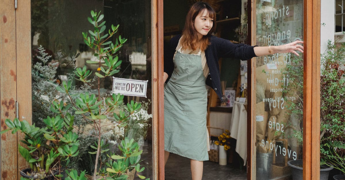 Do stores on Takeshita street open the 1st of January? - Tranquil florist in apron opening glass door of flower shop in daytime in city Do stores on Takeshita street open the 1st of January? - Tranquil florist in apron opening glass door of flower shop in daytime in city