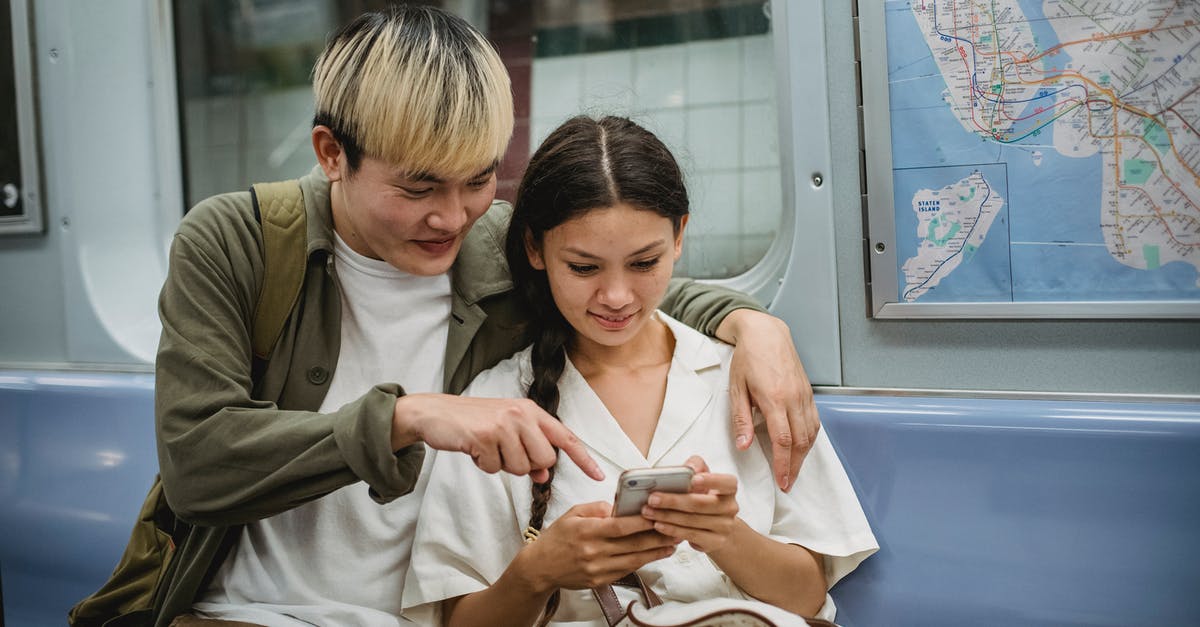 Do we have to share overnight train rooms in Europe? - Happy young trendy Asian guy hugging smiling girlfriend and pointing at smartphone screen while commuting by subway train Do we have to share overnight train rooms in Europe? - Happy young trendy Asian guy hugging smiling girlfriend and pointing at smartphone screen while commuting by subway train