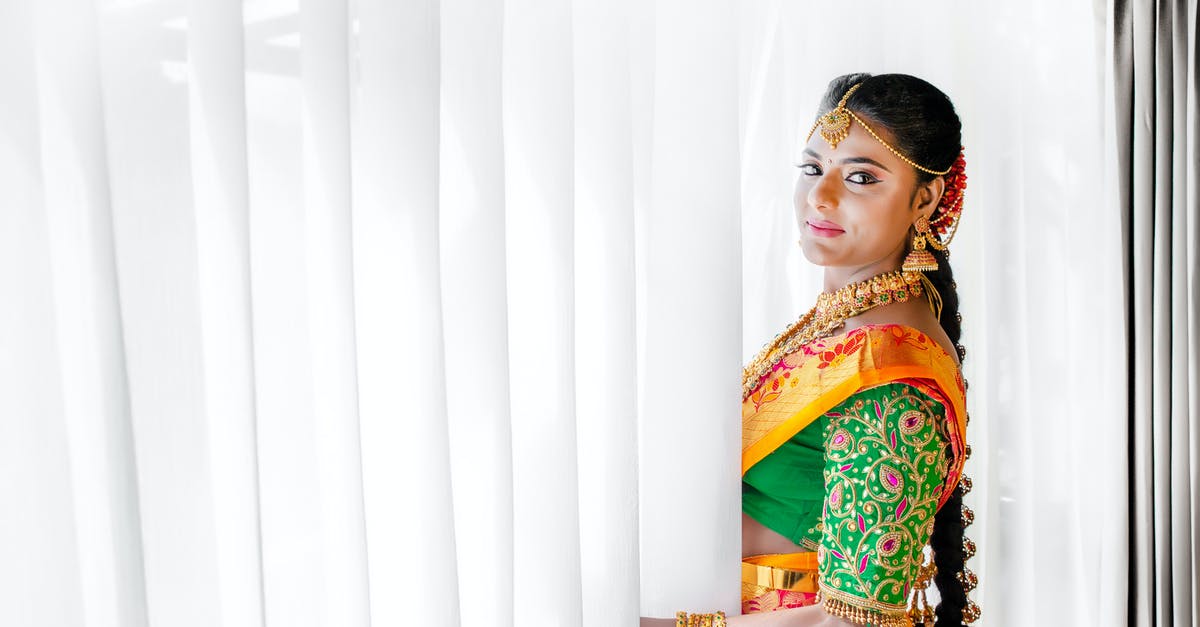 Do you need to declare jewelry when flying? - Woman in Red and Yellow Floral Dress Standing Beside White Curtain