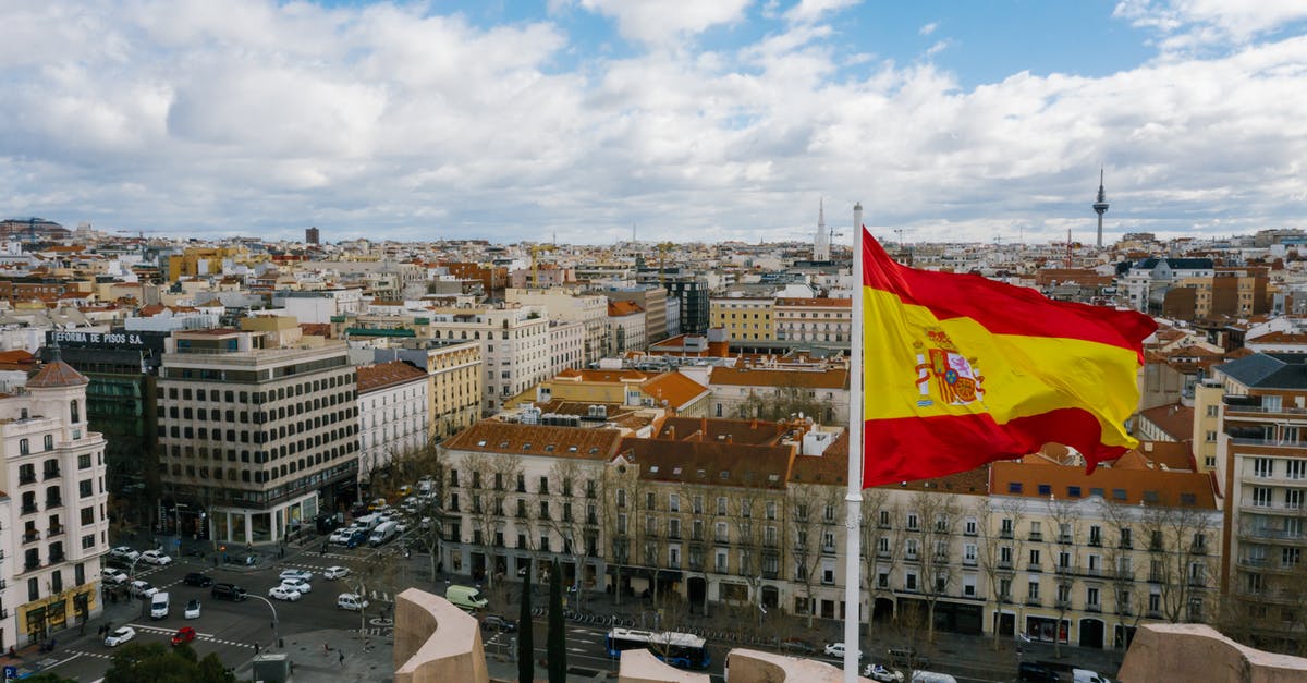 Documentation for 9yr old Spanish national traveling to UK - Drone view of Spanish city with aged buildings and national flag under cloudy blue sky Documentation for 9yr old Spanish national traveling to UK - Drone view of Spanish city with aged buildings and national flag under cloudy blue sky