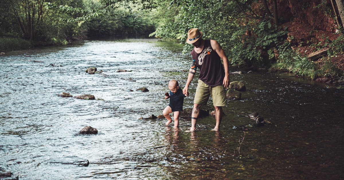 Documentation for one parent traveling with infant, Australia to Japan - Photo of Man Holding His Child While Walking in the River Documentation for one parent traveling with infant, Australia to Japan - Photo of Man Holding His Child While Walking in the River