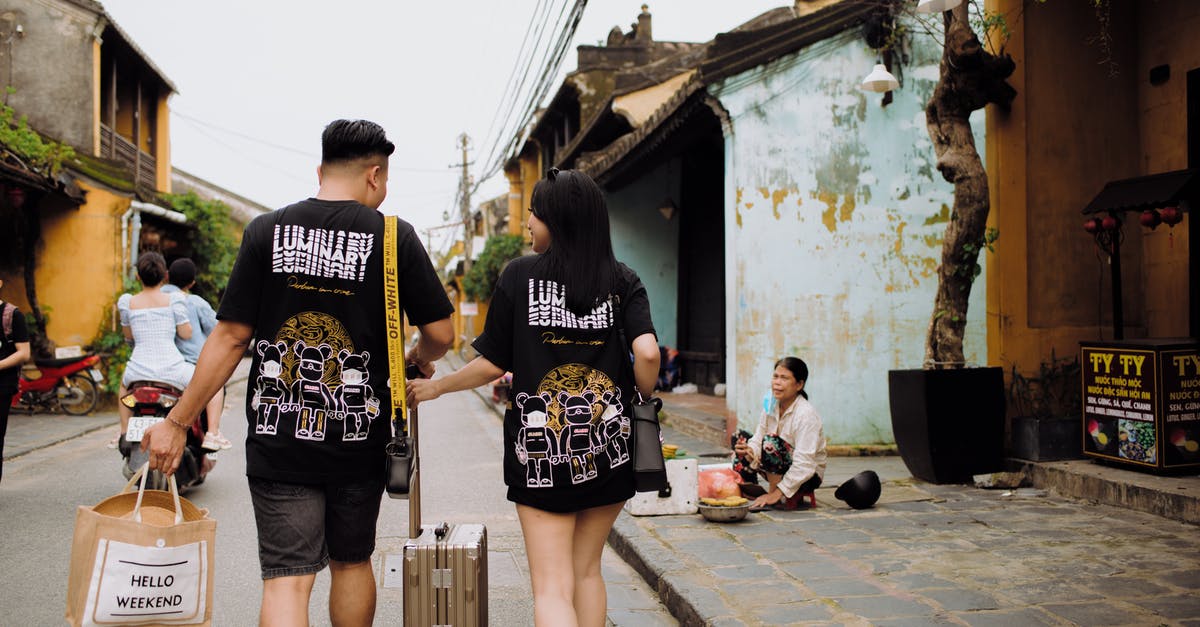 Does a group travelling to the UK apply for their visas together or individually? - Unrecognizable couple of travelers walking on urban road