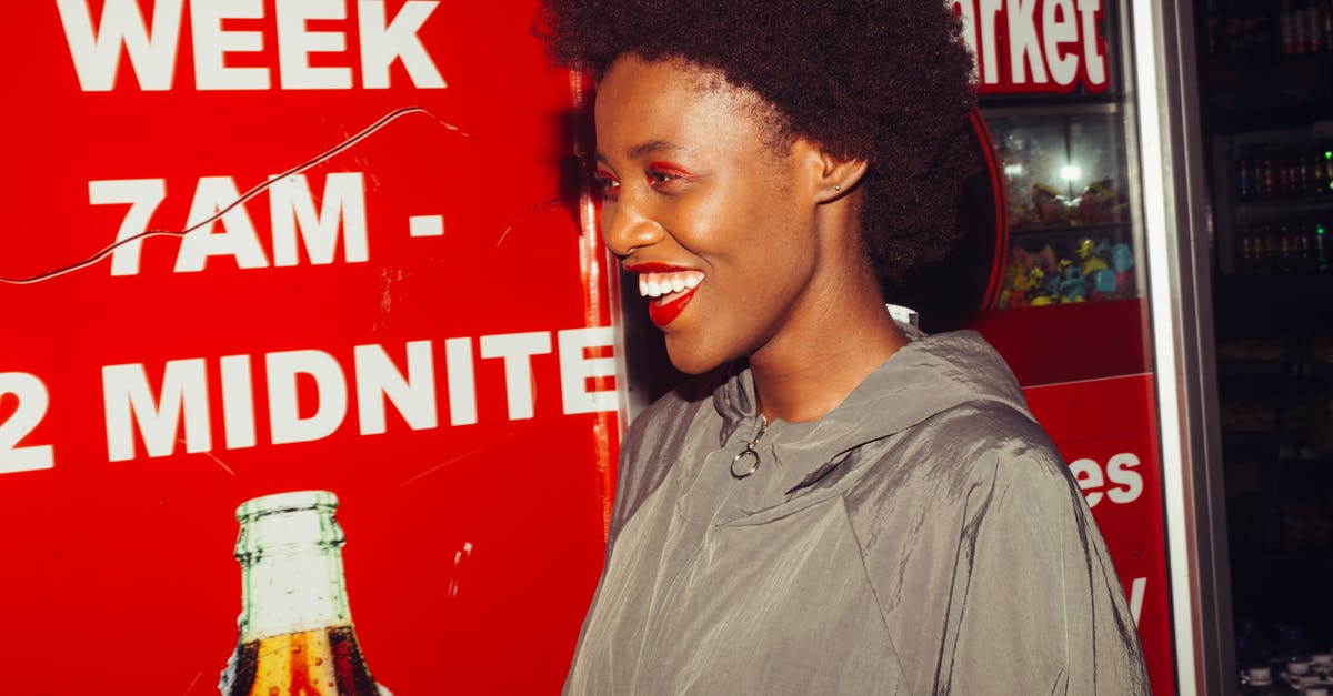 Does Estonia have discount supermarket chains like Aldi and Lidl? - Side view of laughing African American female in outerwear standing near advertising space in supermarket looking away Does Estonia have discount supermarket chains like Aldi and Lidl? - Side view of laughing African American female in outerwear standing near advertising space in supermarket looking away