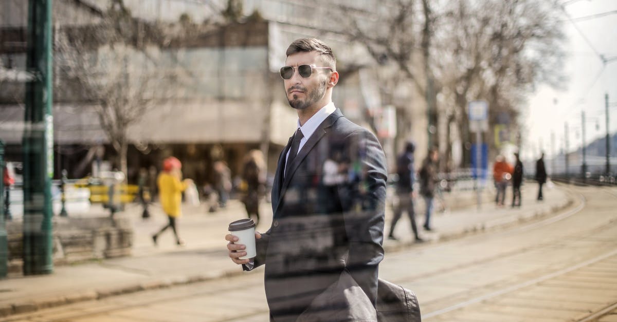 Does my Polish work permit let me travel through the EU? - Through glass view of bearded man in suit and eyeglasses looking away while standing with coffee on city street Does my Polish work permit let me travel through the EU? - Through glass view of bearded man in suit and eyeglasses looking away while standing with coffee on city street
