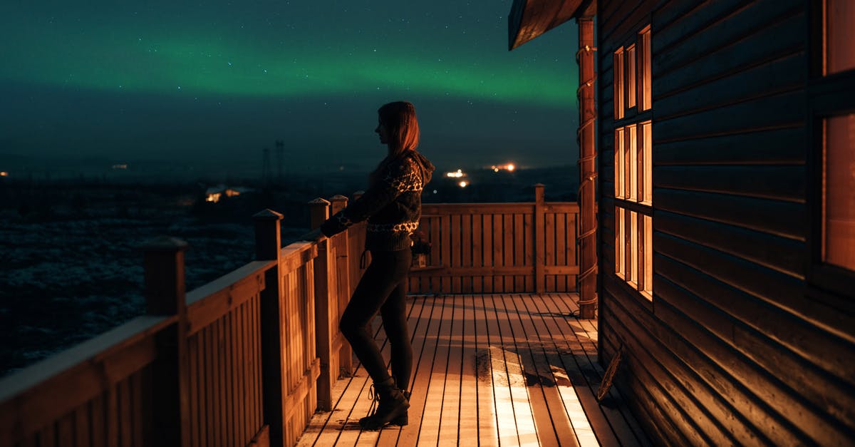 Does night-driving-friendly, polarized eye-wear exist? - Side view of anonymous female in casual wear standing on wooden balcony of house and looking at majestic polar lights in dark sky Does night-driving-friendly, polarized eye-wear exist? - Side view of anonymous female in casual wear standing on wooden balcony of house and looking at majestic polar lights in dark sky