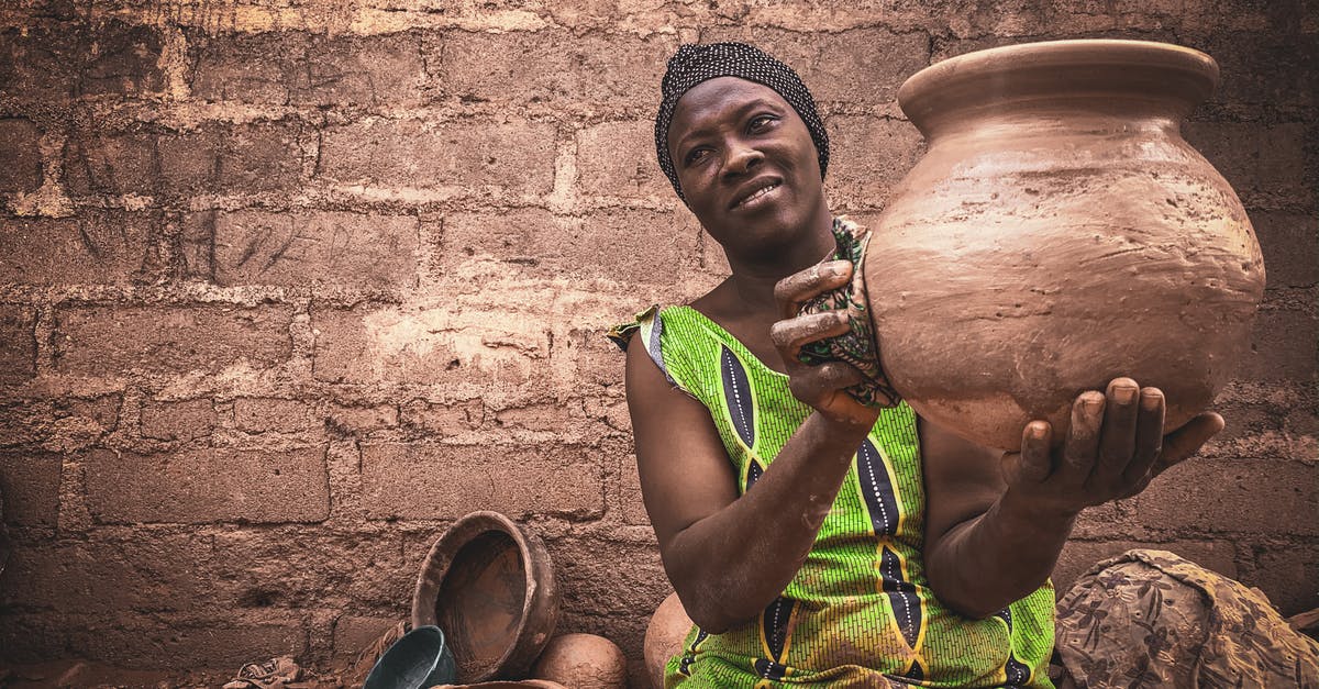 Does occupation show on a one visa affect your chances of getting visa for another country? - Smiling middle aged ethnic female in traditional dress and turban demonstrating handmade clay pot while sitting on street against shabby wall