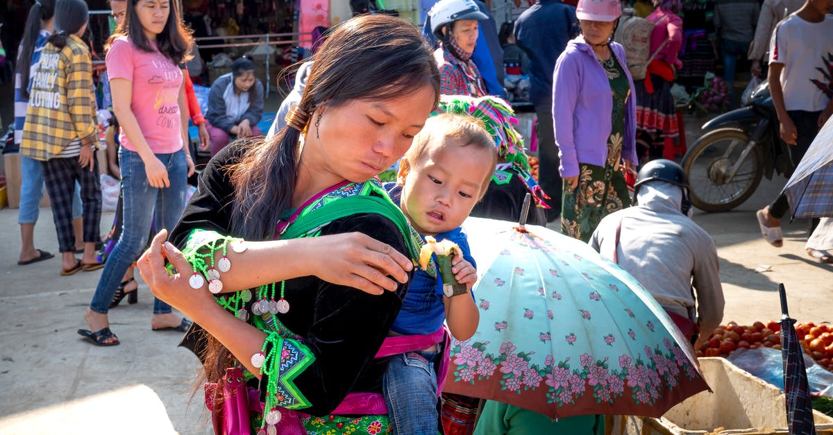 Does travelling to Venezuela in 2016 help or hinder the economic situation for local people? [closed] - Asian mom carrying baby with sweet rice treat in market