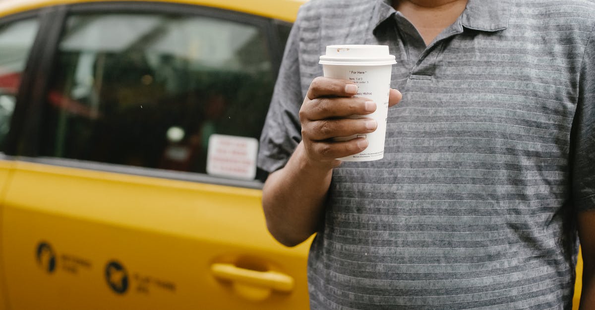 Drink driving ban in the UK applying for a Russian visa - Unrecognizable male in casual outfit with cup of takeaway coffee standing near yellow taxi on city in street during break Drink driving ban in the UK applying for a Russian visa - Unrecognizable male in casual outfit with cup of takeaway coffee standing near yellow taxi on city in street during break