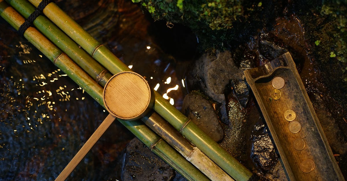 Drinking from the Chalice Well in Glastonbury (Sacred Spring in England) - Bamboo water pipes with dipper near brook Drinking from the Chalice Well in Glastonbury (Sacred Spring in England) - Bamboo water pipes with dipper near brook