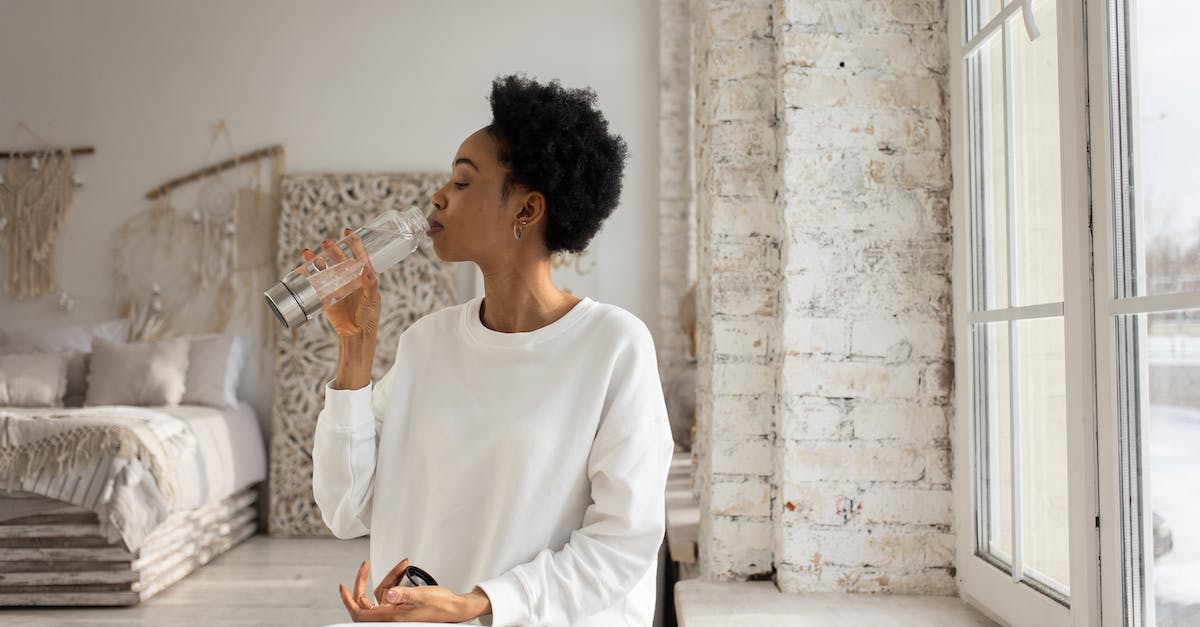 Drinking tap water in India - Woman in White Long Sleeve Shirt Sitting on Floor While Drinking
