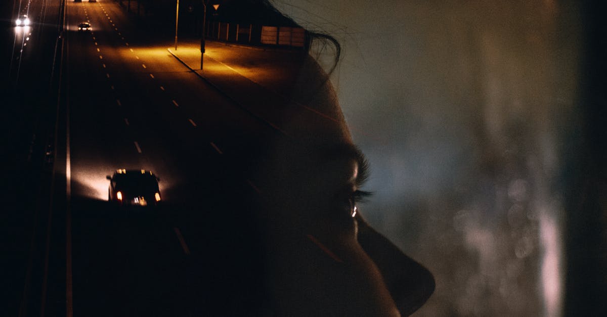 Driving a rental car through Colorado - Side view crop female sitting in car behind window glass reflecting road with moving cars and street lights at night Driving a rental car through Colorado - Side view crop female sitting in car behind window glass reflecting road with moving cars and street lights at night