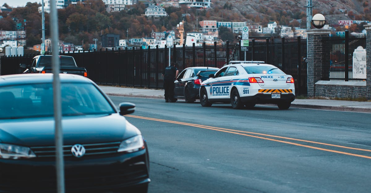 driving abroad with own car and local law on modifications, differences between what's is legal on a car and what isn't - Anonymous policeman checking car on street driving abroad with own car and local law on modifications, differences between what's is legal on a car and what isn't - Anonymous policeman checking car on street