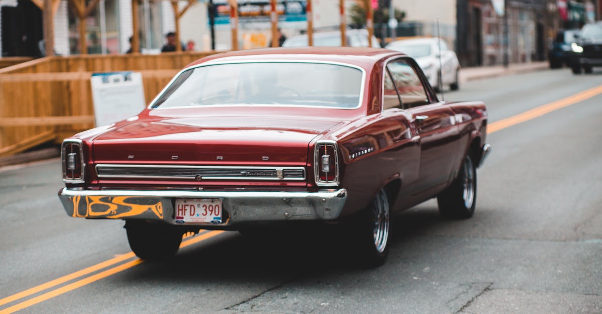 Driving license in California - Unrecognizable driver in retro car on road near urban buildings Driving license in California - Unrecognizable driver in retro car on road near urban buildings