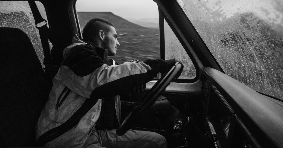 Driving non-GB registered car inside Low Emission Zone - Side view of concentrate young male traveler in warm outerwear driving car along rocky terrain during snowfall Driving non-GB registered car inside Low Emission Zone - Side view of concentrate young male traveler in warm outerwear driving car along rocky terrain during snowfall