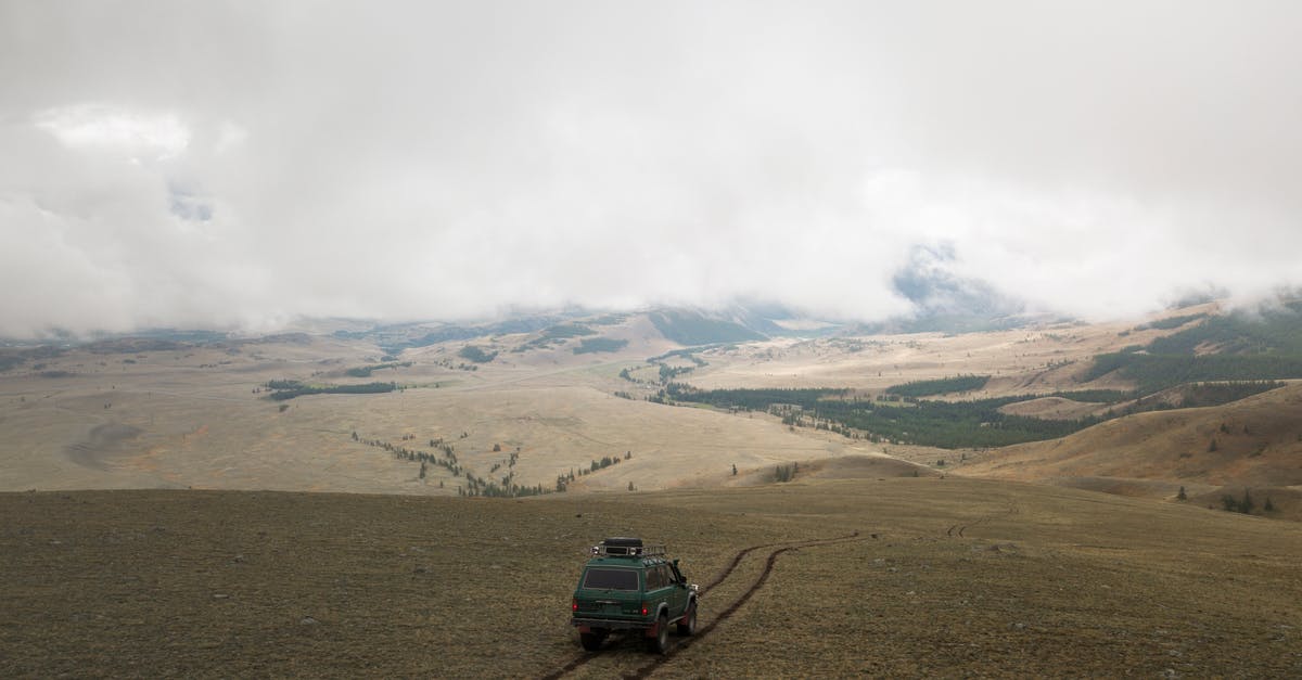 Driving SUVs in the Namibian desert - Aerial view of old green SUV car driving along empty endless valley under thick clouds Driving SUVs in the Namibian desert - Aerial view of old green SUV car driving along empty endless valley under thick clouds