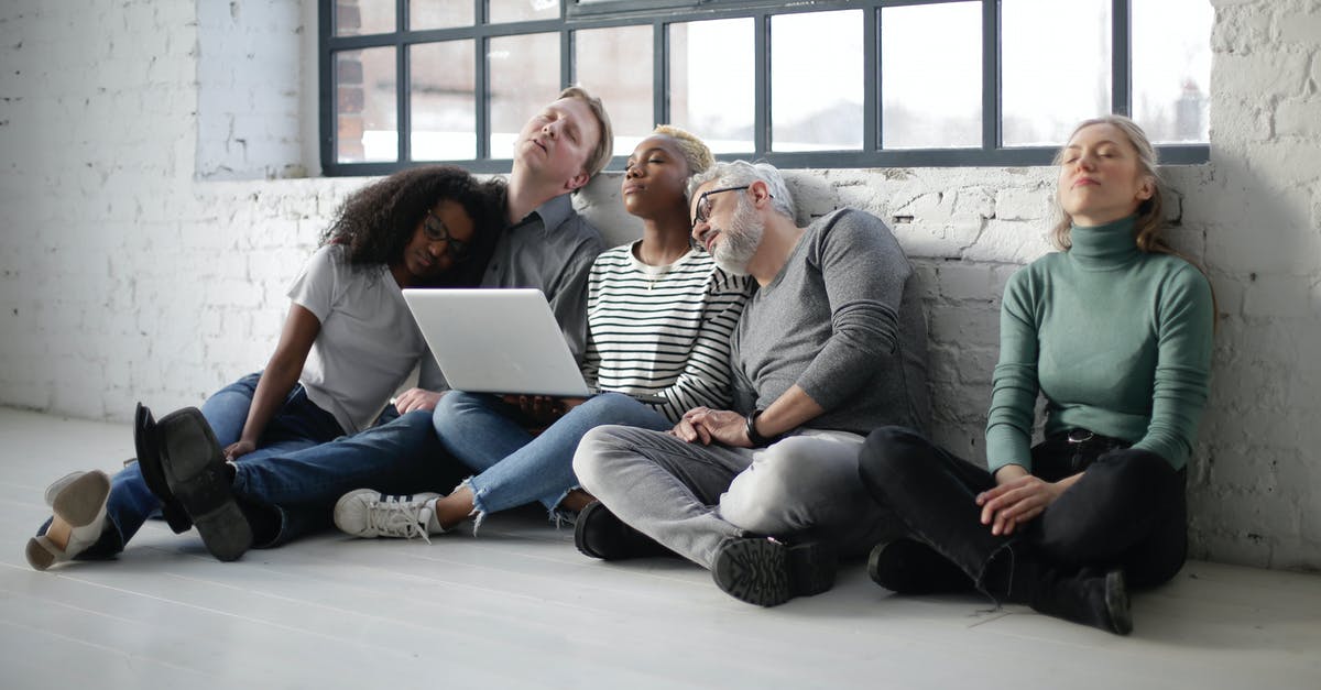 DS-160 - B1/B2 visa - Work/Education/Training - How to fill the section as full-time employee and part-time student [closed] - Tired diverse colleagues sitting on floor leaning on wall while having break holding netbook on lap in light studio