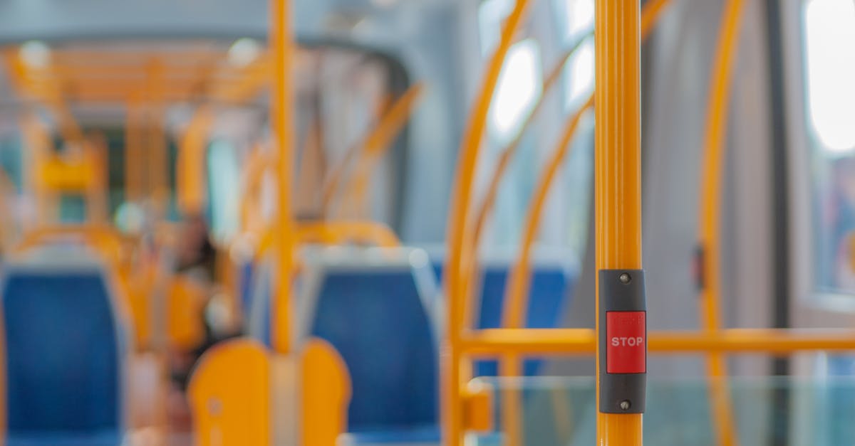 Early-morning food at Népliget bus station in Budapest? - Red stop button on yellow handrail in modern empty public bus during daytime