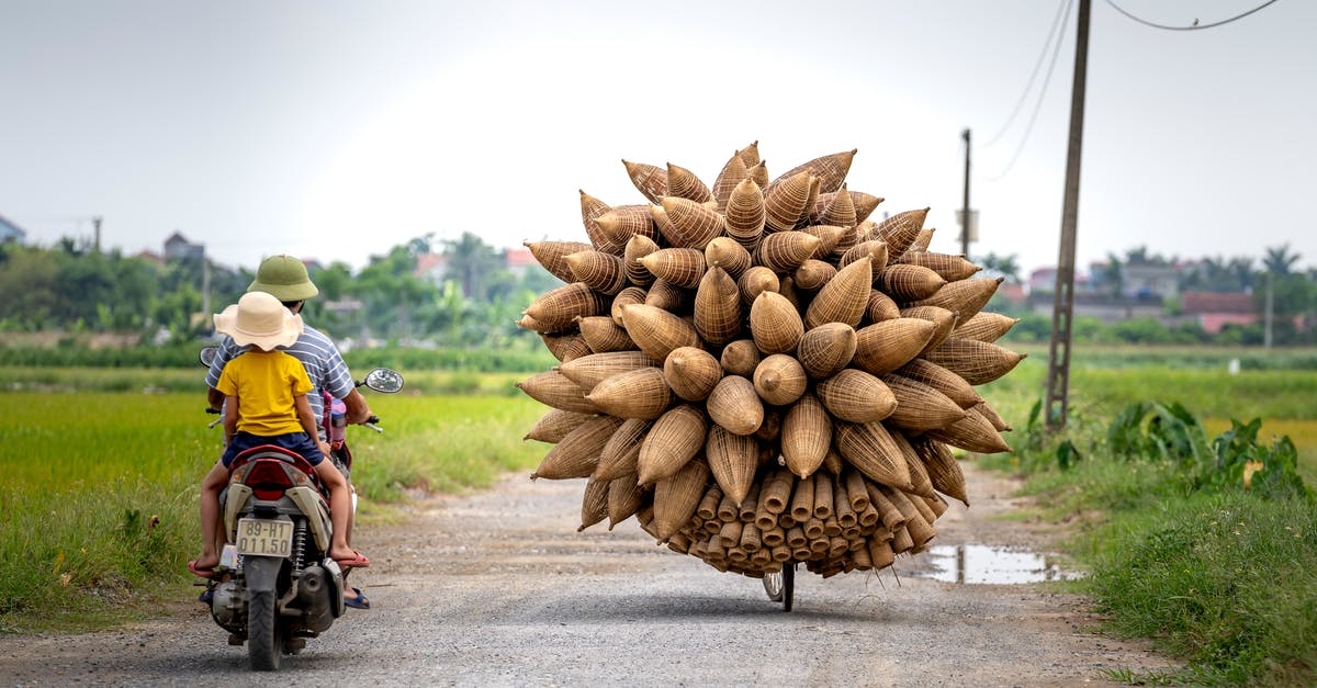 Easiest way to carry two laptops to India and back from USA? [duplicate] - People driving motorcycle near bicycle with bamboo fish traps in countryside