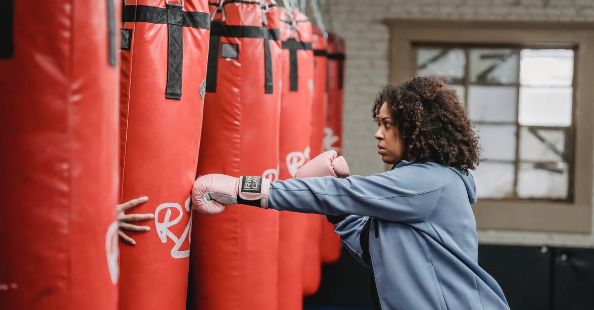 EasyJet underseat bag size - Focused black woman hitting punching bag held by trainer EasyJet underseat bag size - Focused black woman hitting punching bag held by trainer