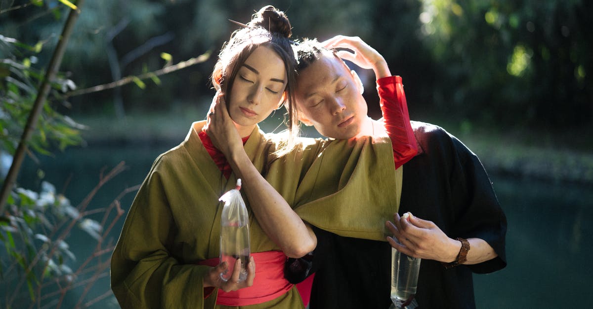 Eating fish eye in Japan - Man And Woman With Eyes Closed Holding Plastics With Fish Eating fish eye in Japan - Man And Woman With Eyes Closed Holding Plastics With Fish